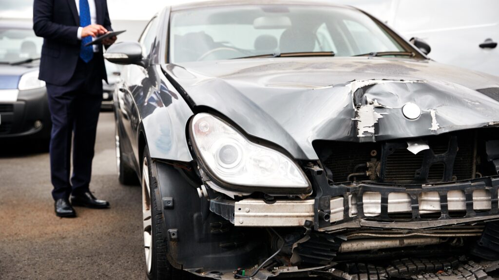 Insurance adjuster looking at totaled car